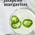 overhead view of jalapeño margarita recipe on a white marble surface, with text overlay that reads "spicy jalapeno margaritas"