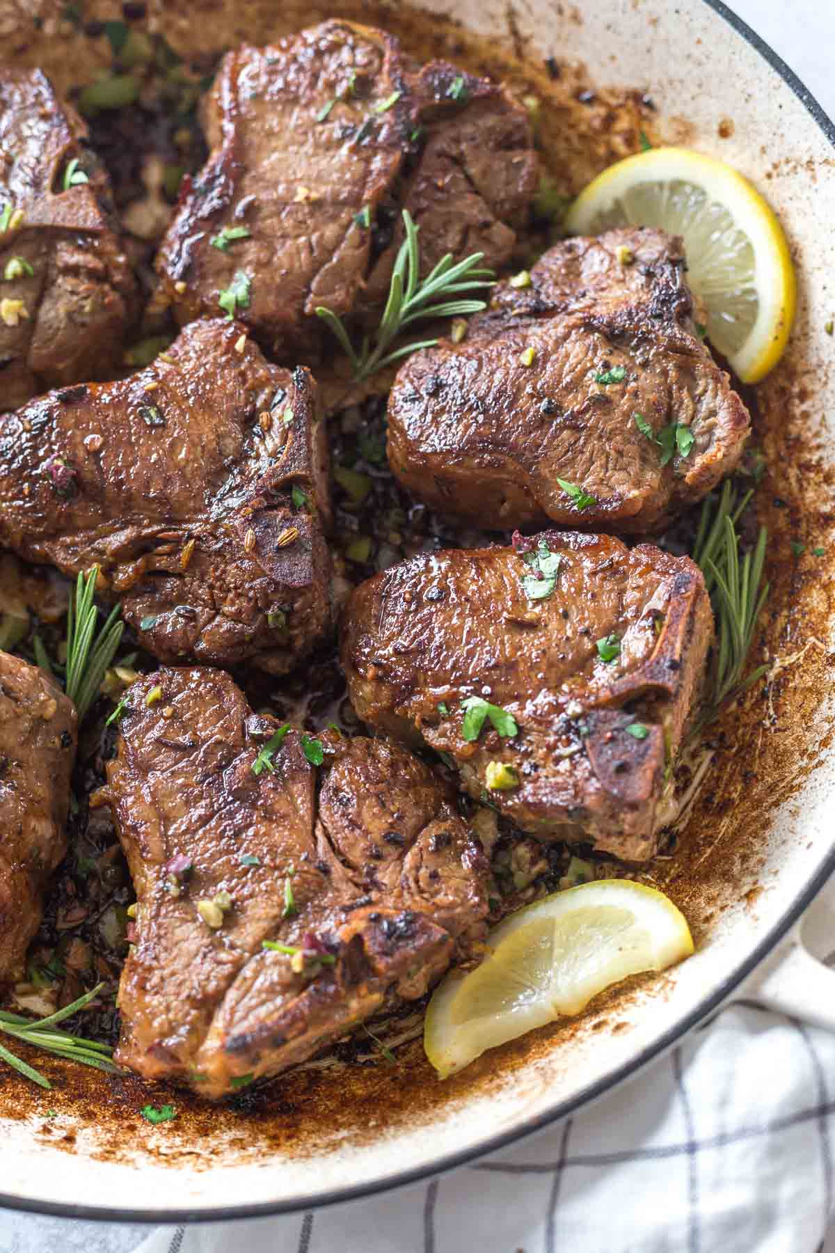 pan fried lamb chops recipe with rosemary and olives in a large white skillet