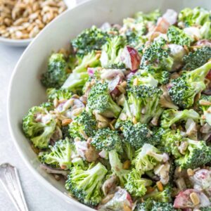 easy broccoli salad recipe with bacon and grapes in a large white serving bowl