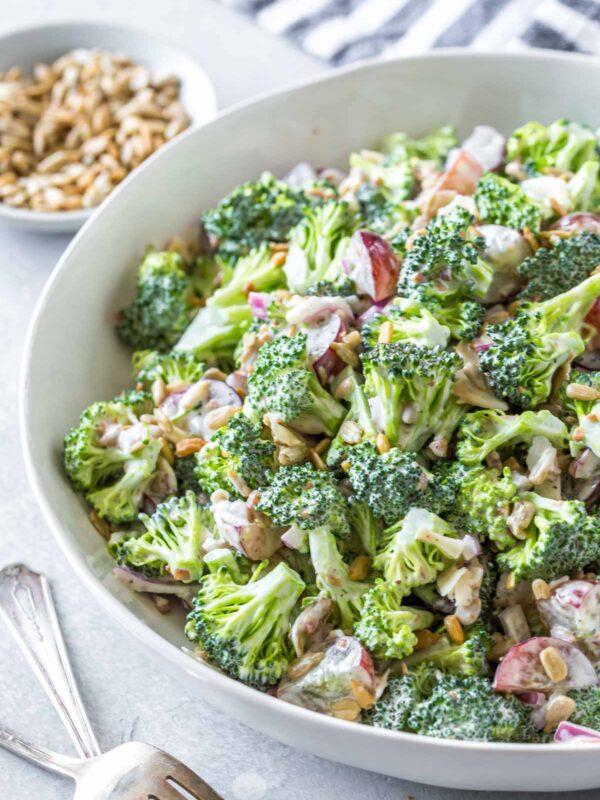 easy broccoli salad recipe with bacon and grapes in a large white serving bowl