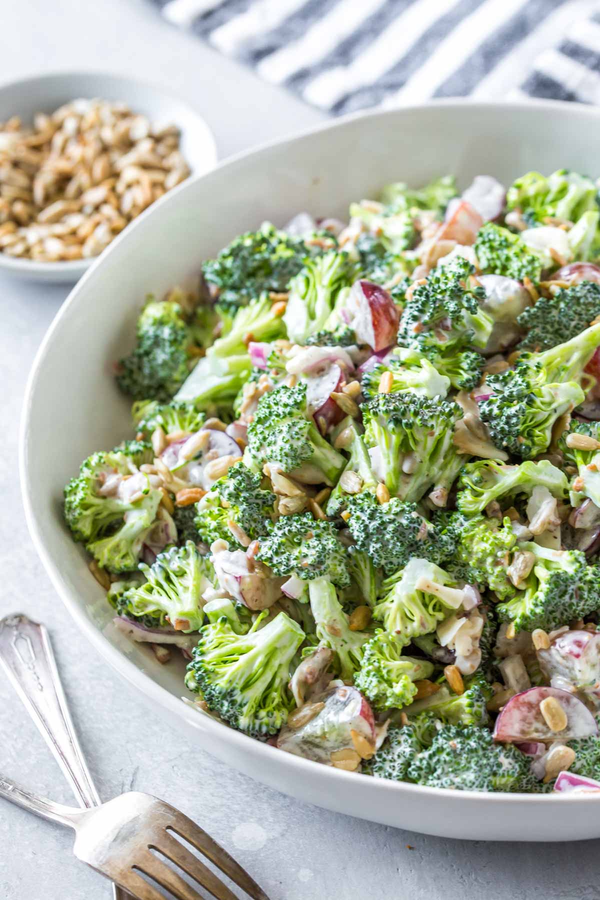 easy broccoli salad recipe with bacon and grapes in a large white serving bowl