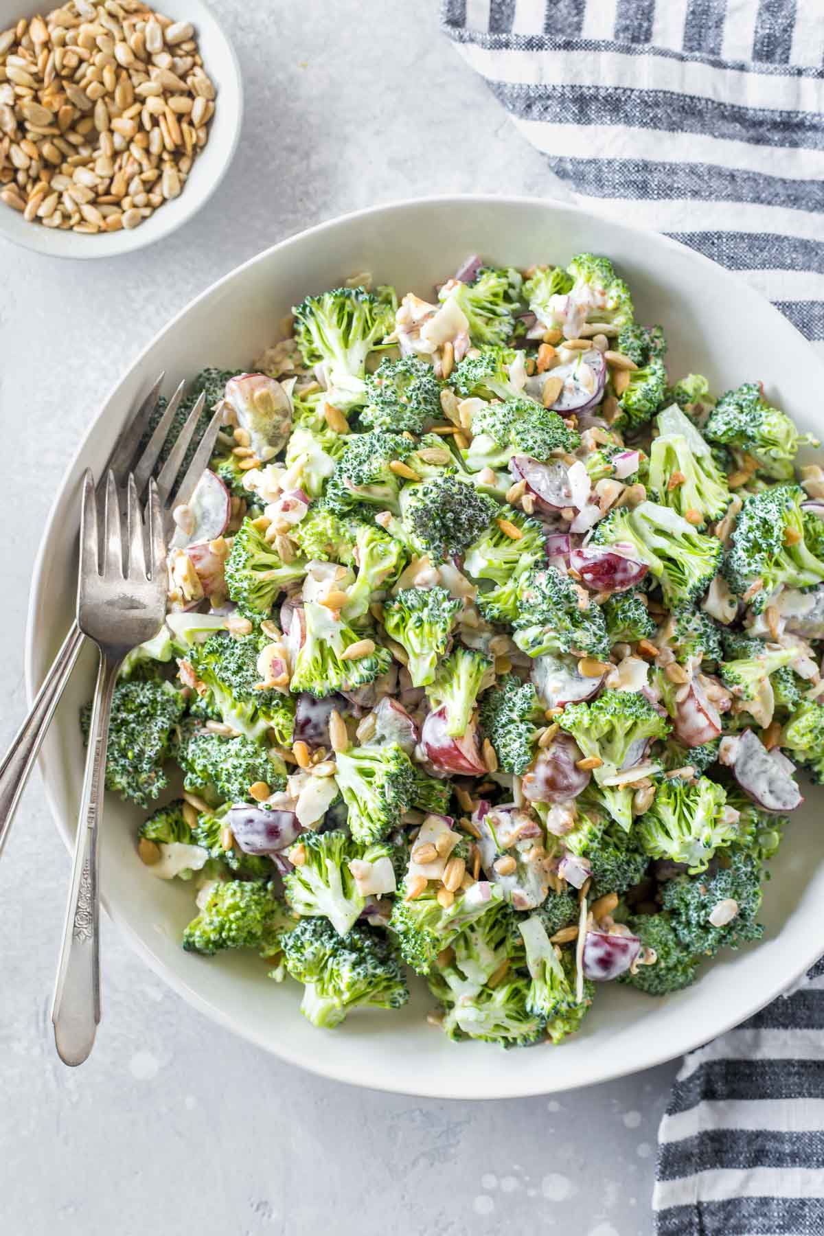 overhead shot of an easy broccoli salad recipe with bacon and grapes in a large white serving bowl