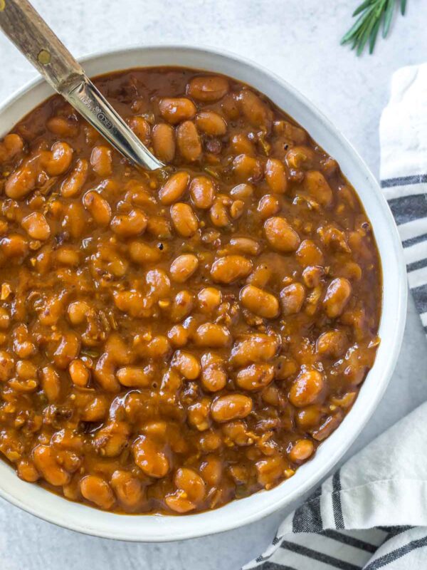 instant pot baked beans in a serving dish with a wooden handled spoon on a concrete surface