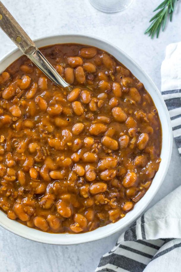 instant pot baked beans in a serving dish with a wooden handled spoon on a concrete surface