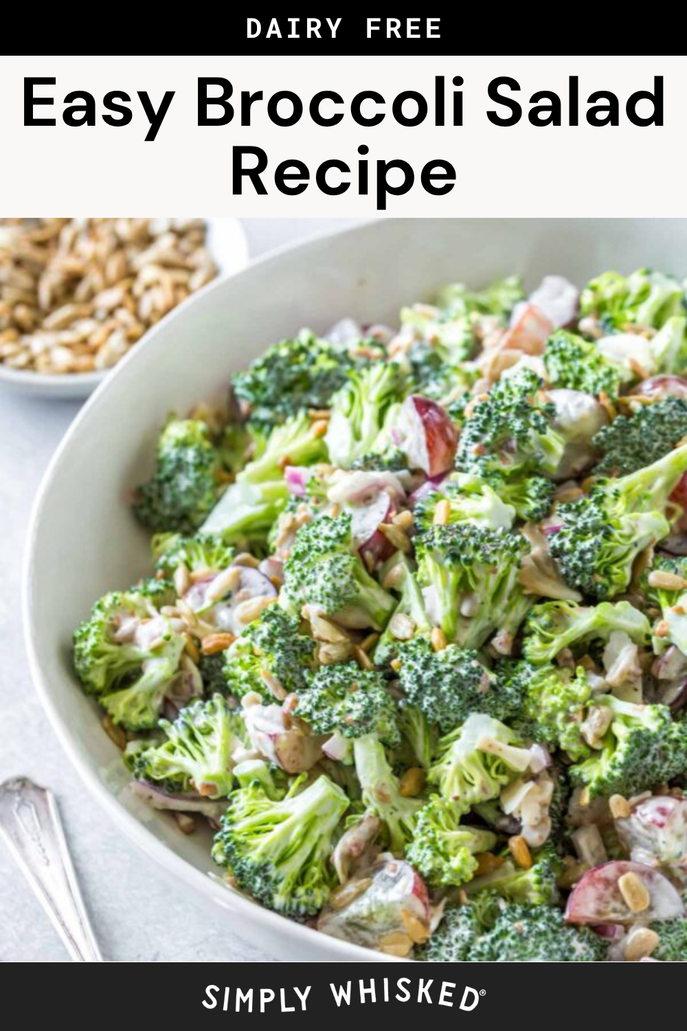 A bowl of broccoli salad with sunflower seeds, red onions, and dressing sits on a table next to a spoon and a small bowl of sunflower seeds. Text above reads: “Easy Broccoli Salad Recipe, Dairy Free.” This simple yet delicious broccoli salad recipe can easily be customized—try adding crispy bacon or sweet grapes for extra flavor and texture.