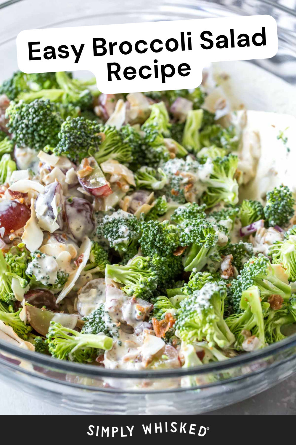 A glass bowl filled with broccoli salad, featuring chopped broccoli, grapes, nuts, and a creamy dressing. The text on the image reads Easy Broccoli Salad Recipe and Simply Whisked, highlighting this easy broccoli salad that’s perfect for any occasion.