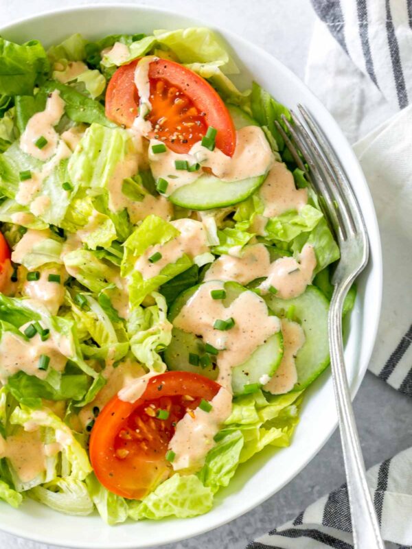 overhead shot of thousand island dressing recipe on a salad of romaine with cucumbers and tomato wedges