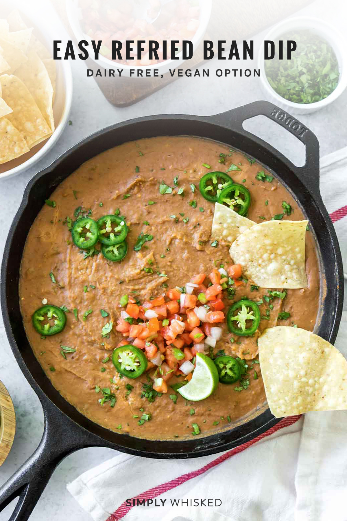 refried bean dip garnished with pico de gallo, jalapenos and salsa in a cast iron skillet, image has text overlay for Pinterest