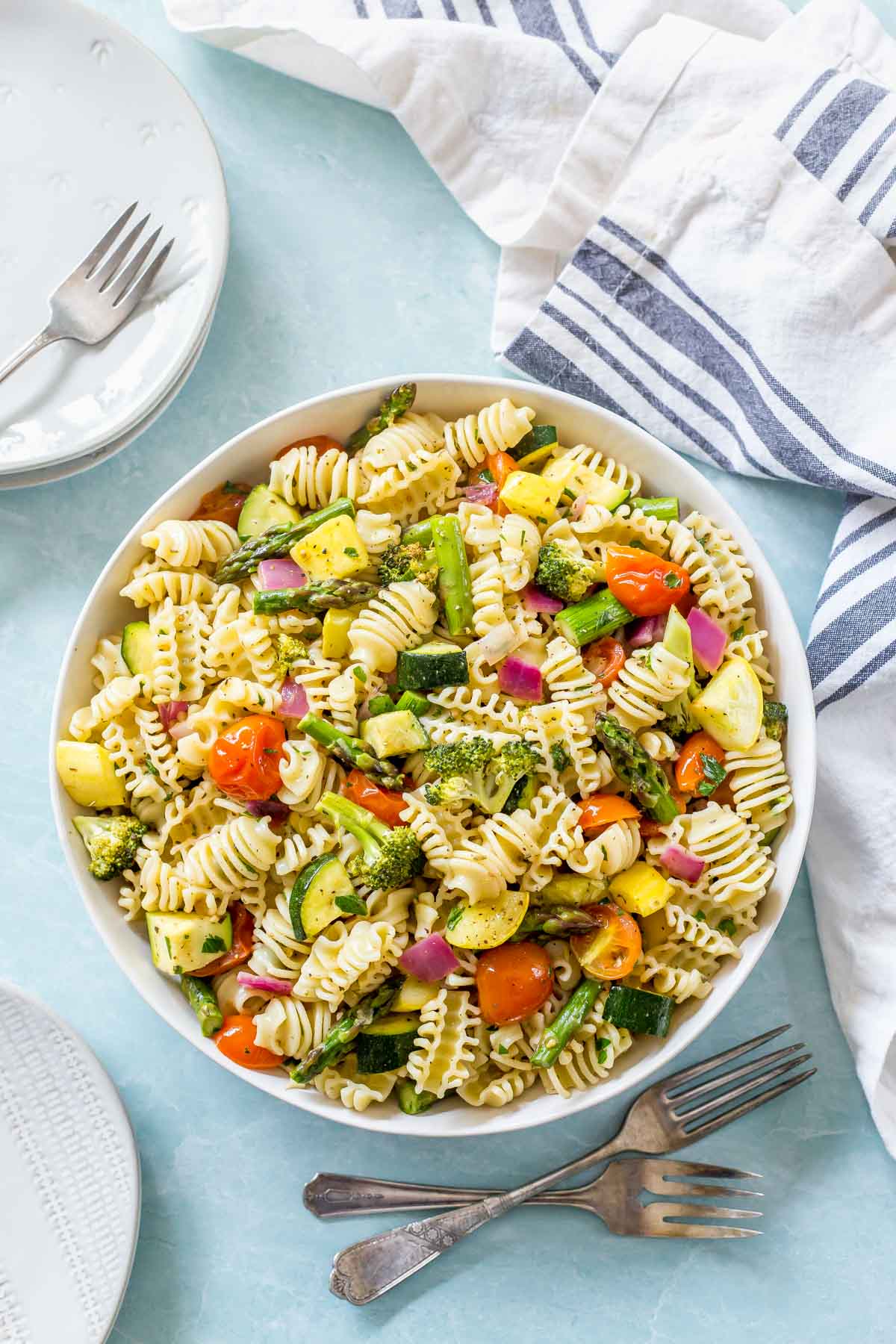 overhead shot of roasted vegetable pasta salad recipe in a while bowl on a light blue surface