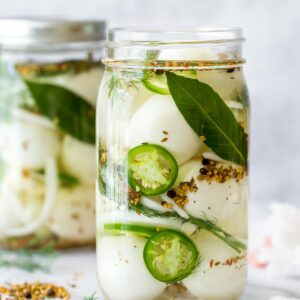 spicy pickled eggs recipe in a mason jar without the lid, a second jar in the background on a white, marble surface