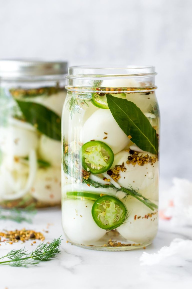 spicy pickled eggs recipe in a mason jar without the lid, a second jar in the background on a white, marble surface
