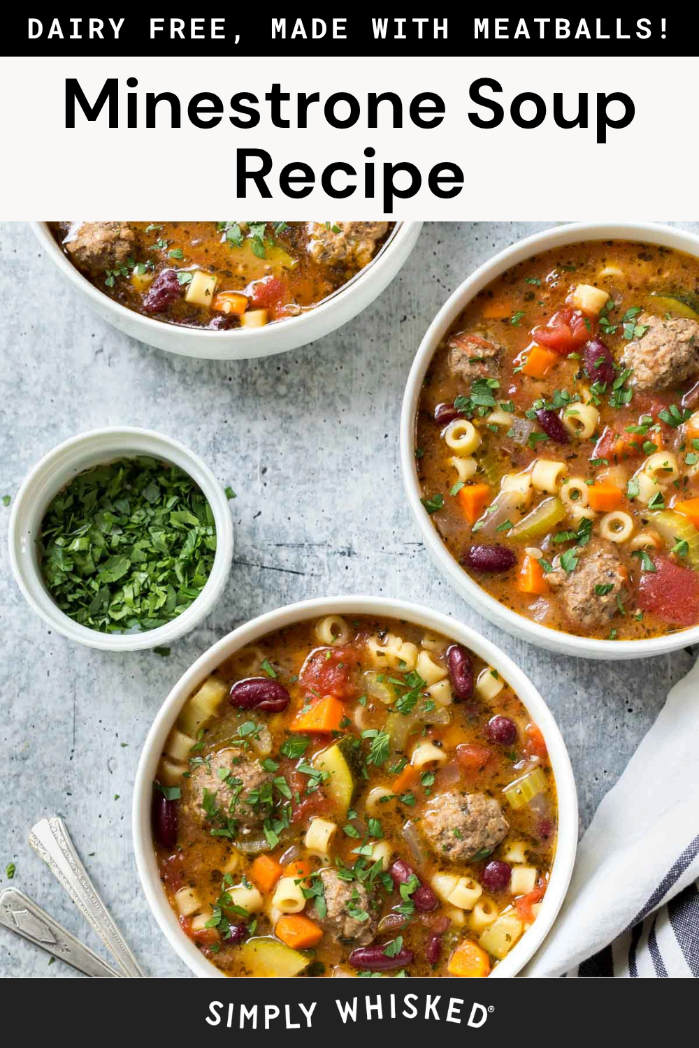 Three bowls of hearty minestrone soup with meatballs, kidney beans, pasta, and fresh vegetables sit invitingly on a table, each garnished with a sprinkle of chopped herbs. A small bowl of herbs and two spoons complete this cozy minestrone soup setting.