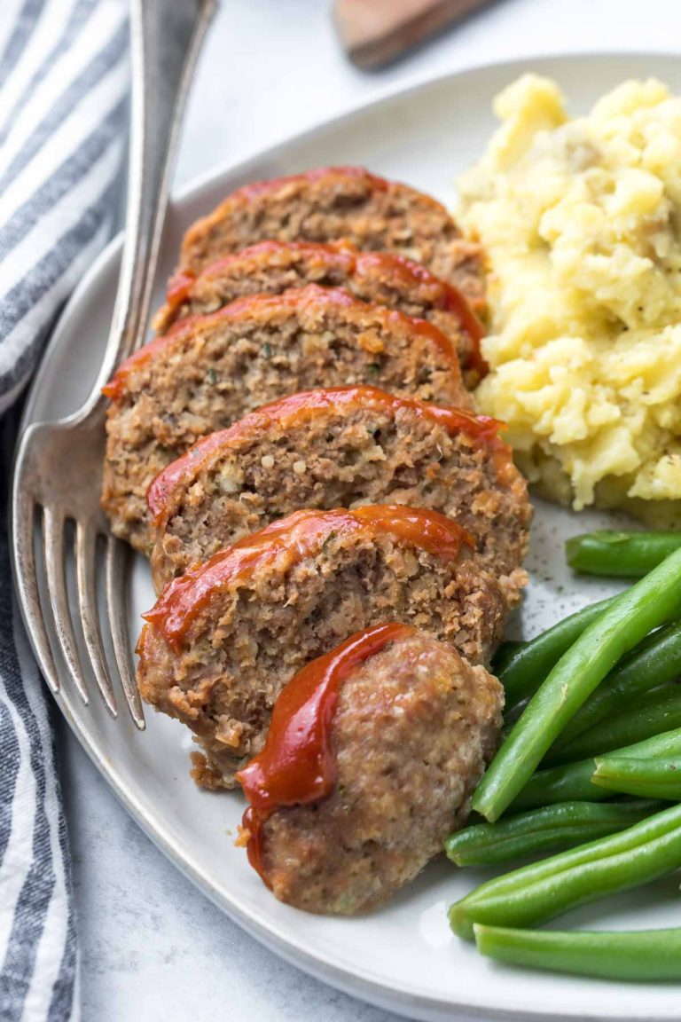closeup of mini meatloaf recipe, sliced on a plate with green beans and mashed potatoes