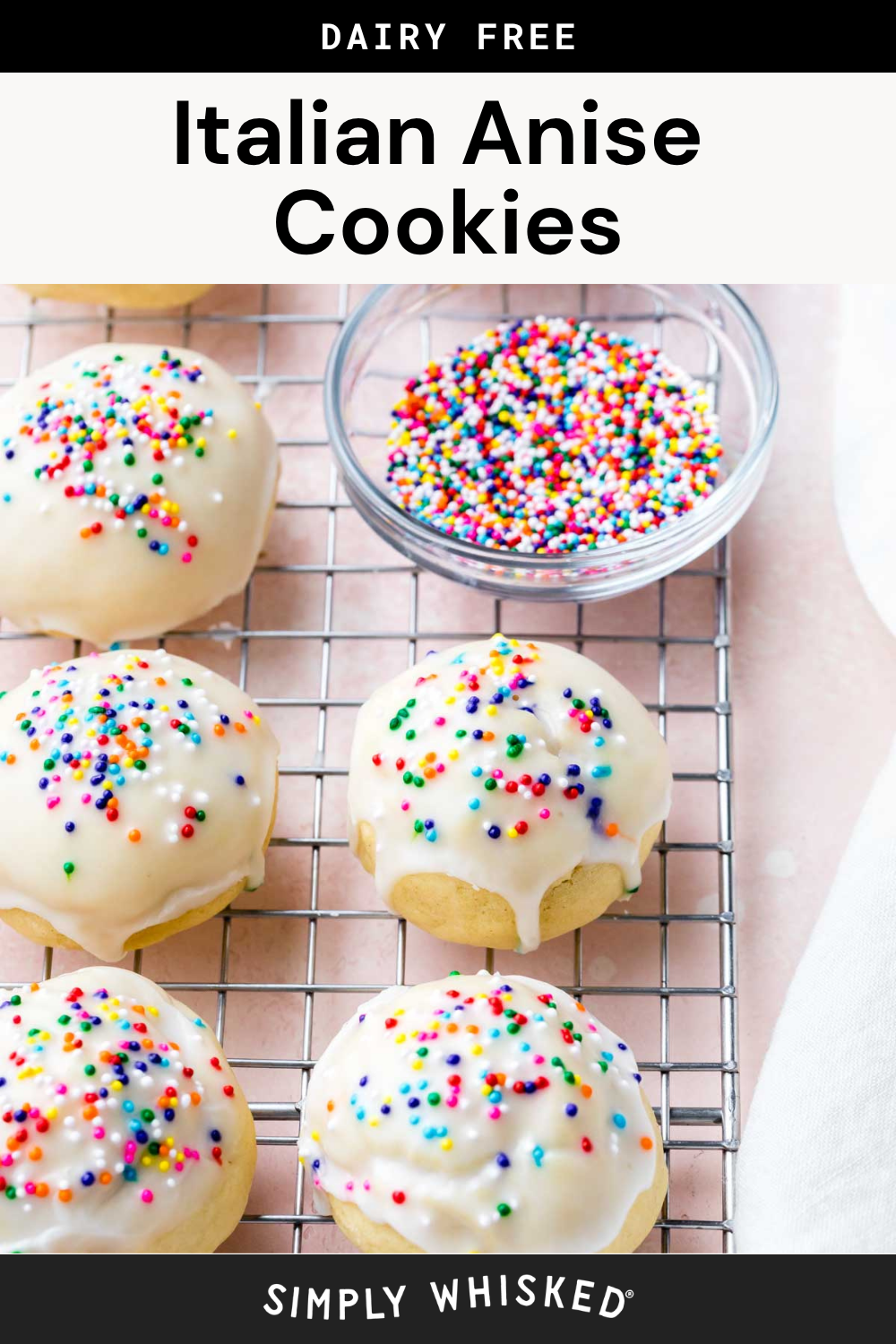 Six iced Italian anise cookies, also known as anisette cookies, with rainbow sprinkles are cooling on a metal rack. A small bowl of extra sprinkles sits nearby. A label above reads Italian Anise Cookies and Simply Whisked appears at the bottom.