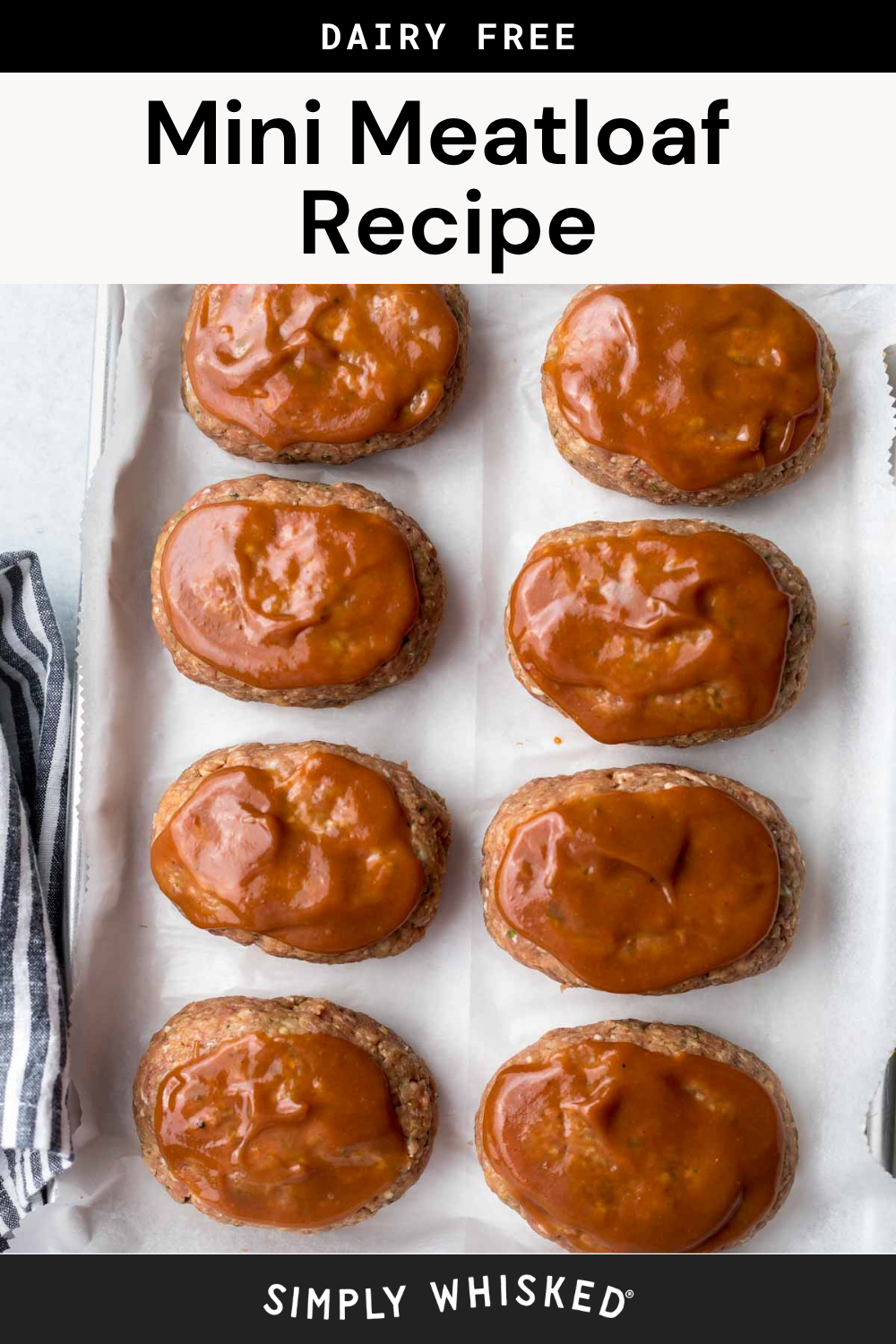 Eight mini meatloaves topped with sauce rest on a parchment-lined baking sheet, viewed from above, perfectly capturing this Mini Meatloaf Recipe. A black and white striped towel sits to the side. Text at the top reads Mini Meatloaf Recipe and Dairy Free.