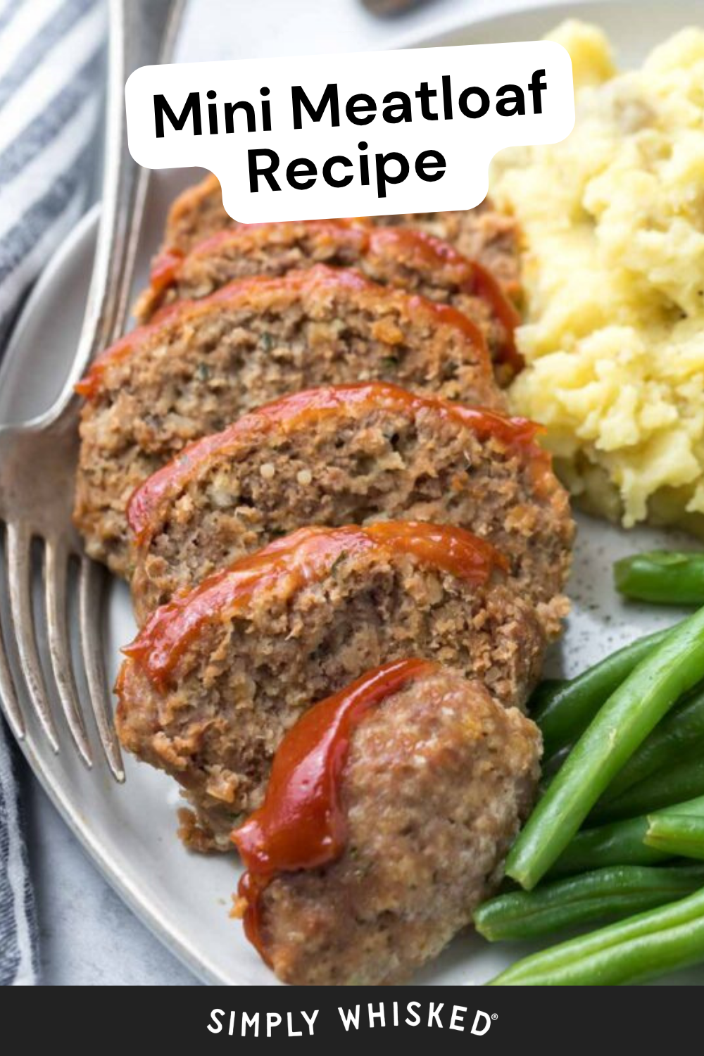 A plate with slices of mini meatloaf topped with ketchup, served alongside creamy mashed potatoes and fresh green beans, with a fork on the side. Text overlay reads Mini Meatloaf Recipe, making it a delicious comfort food classic perfect for weeknight dinners.