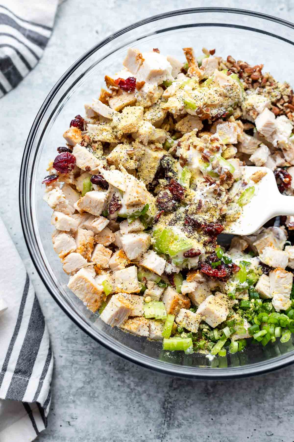 turkey salad recipe with cranberries and pecans being mixed with a rubber spatula