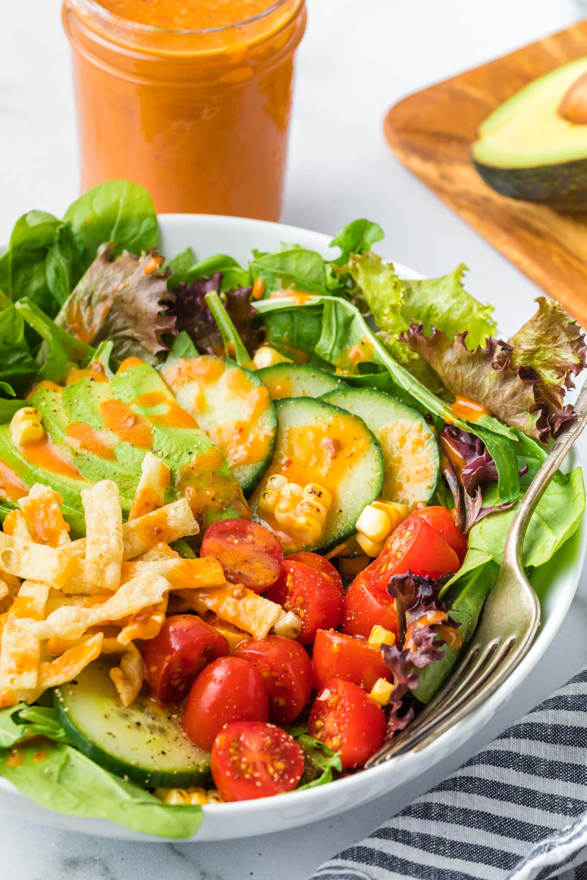 A bowl of salad filled with vegetables and covered in Chipotle salad dressing