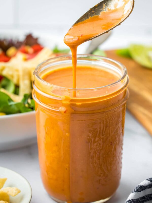 a spoon pouring Chipotle salad dressing into a small mason jar