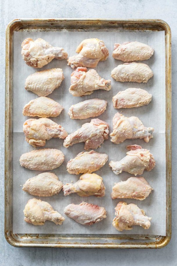 baking sheet lined with parchment paper and rows of raw chicken wings