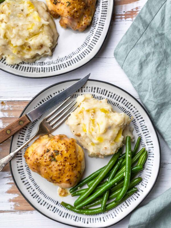 honey mustard glazed chicken thigh on a dinner plat with mashed potatoes and green beans