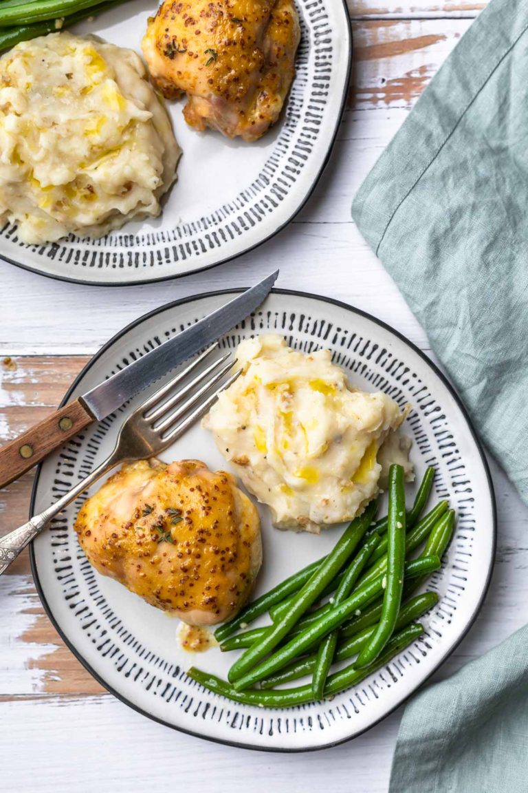 honey mustard glazed chicken thigh on a dinner plat with mashed potatoes and green beans