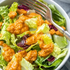 a close up view of a salad with ginger dressing on it and a fork