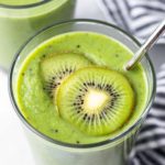 a glass full of kiwi smoothie and topped with two kiwi slices