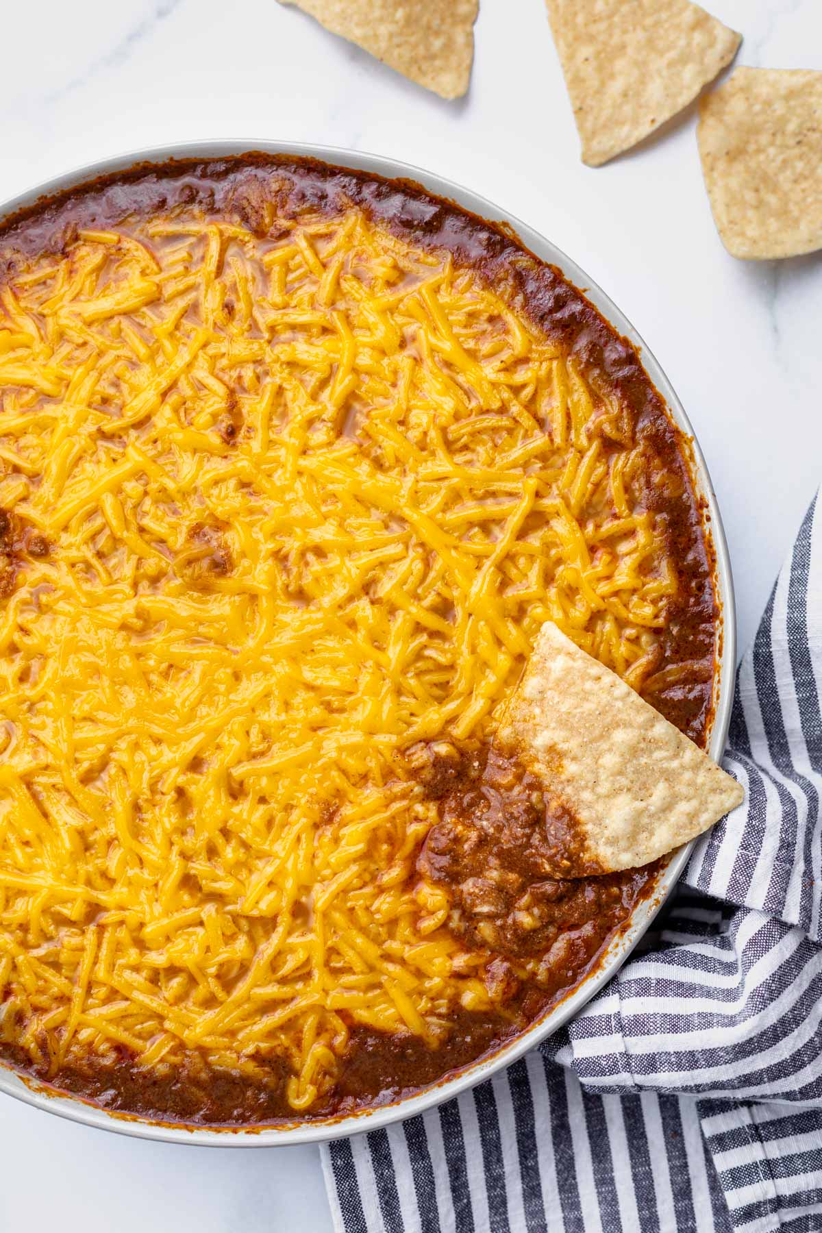 overhead photo of skyline chili dip with a tortilla chip dipped halfway in