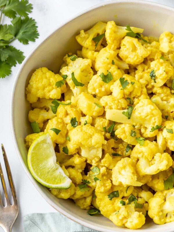 An upclose view of cauliflower curry in a bowl with garnishes