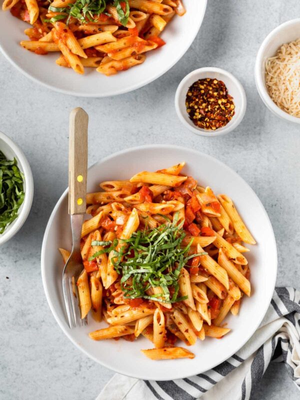 an aerial view of penne arrabbiata with garnishes to the side
