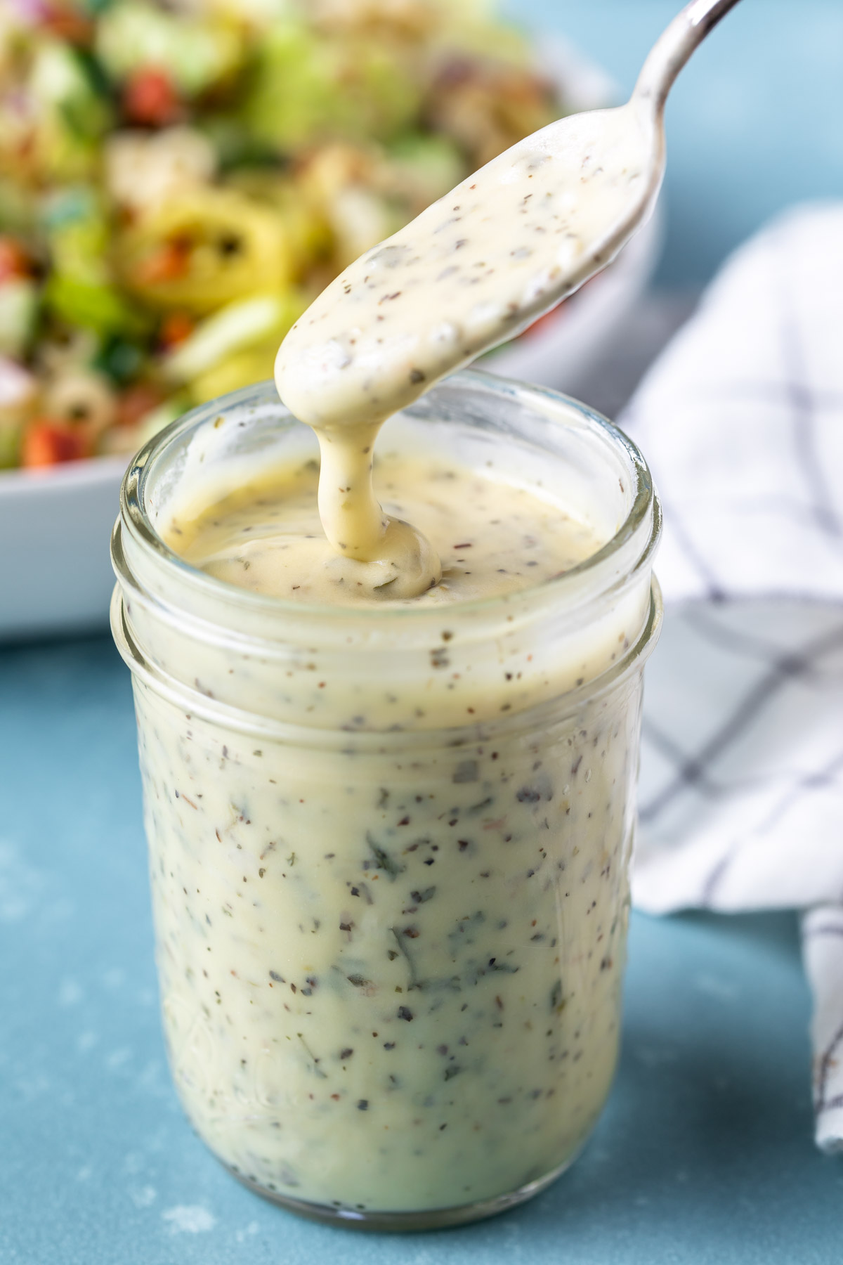 drizzling creamy dressing into a mason jar with a spoon