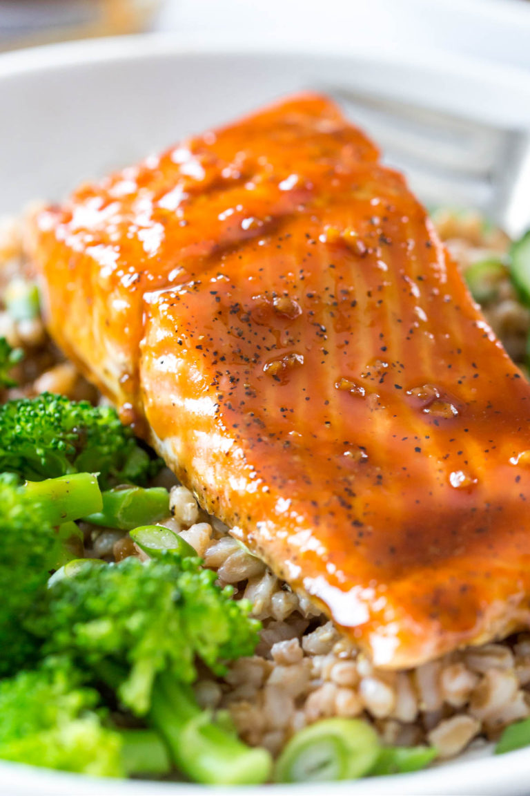 a close up view of maple glazed salmon on top of a bed of rice