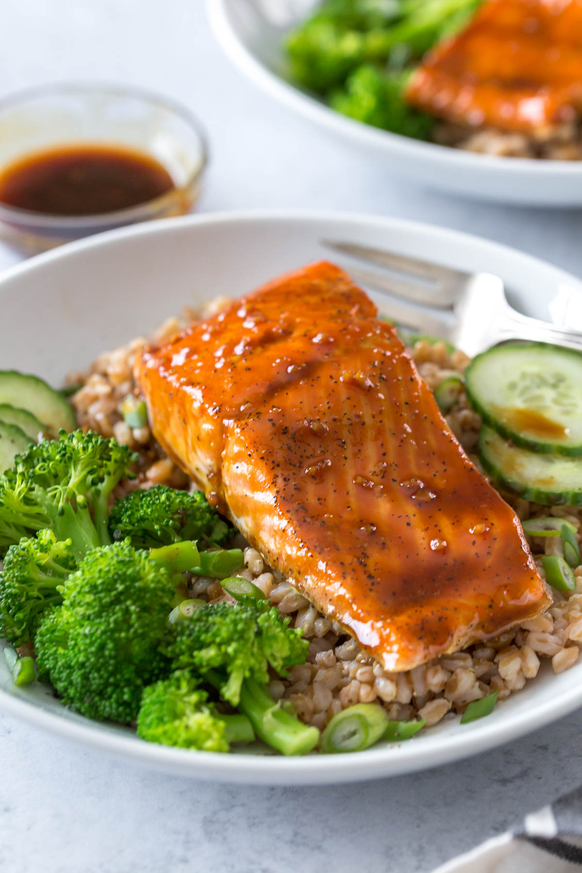 maple glazed salmon on a dinner plate filled with rice, broccoli, and garnished with cucumbers