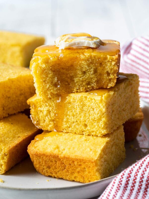 a stack of honey covered cornbread with a slice of butter on top