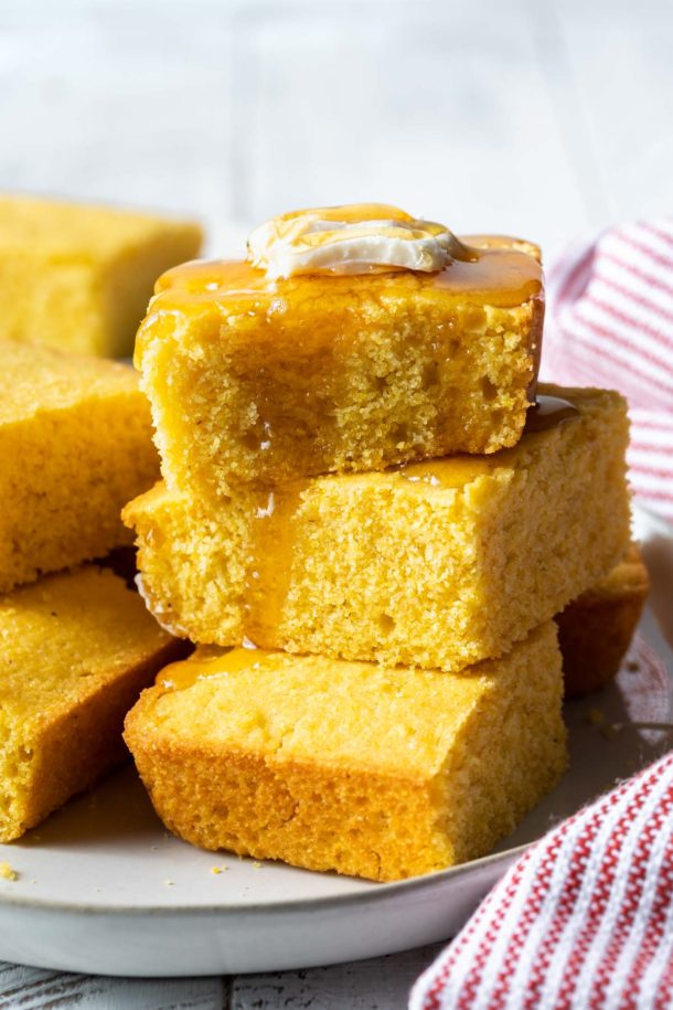 a stack of honey covered cornbread with a slice of butter on top