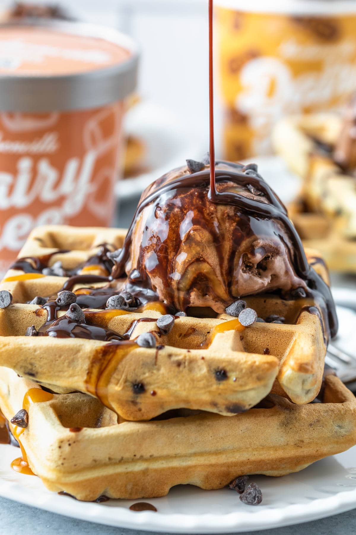 Topping chocolate chip waffles with ice cream and chocolate syrup