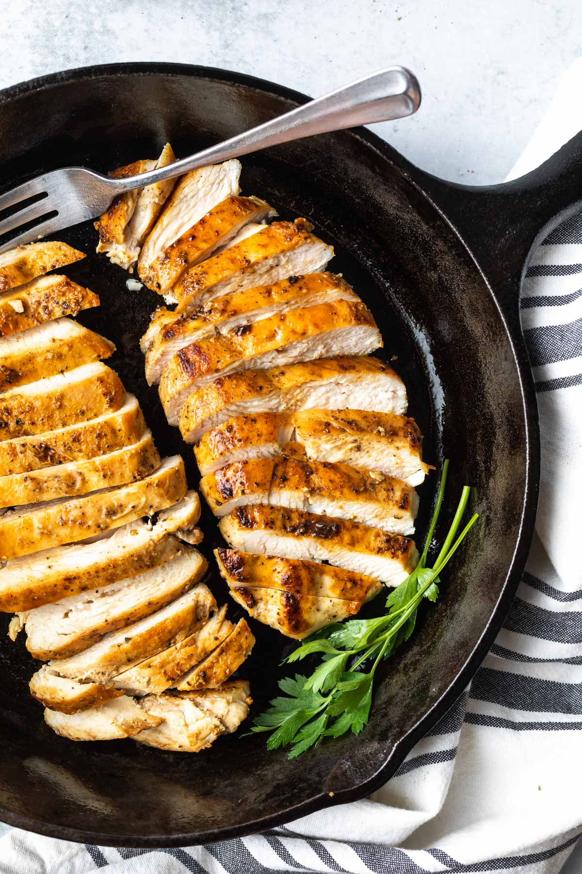 sliced chicken breast in a skillet garnished with parsley