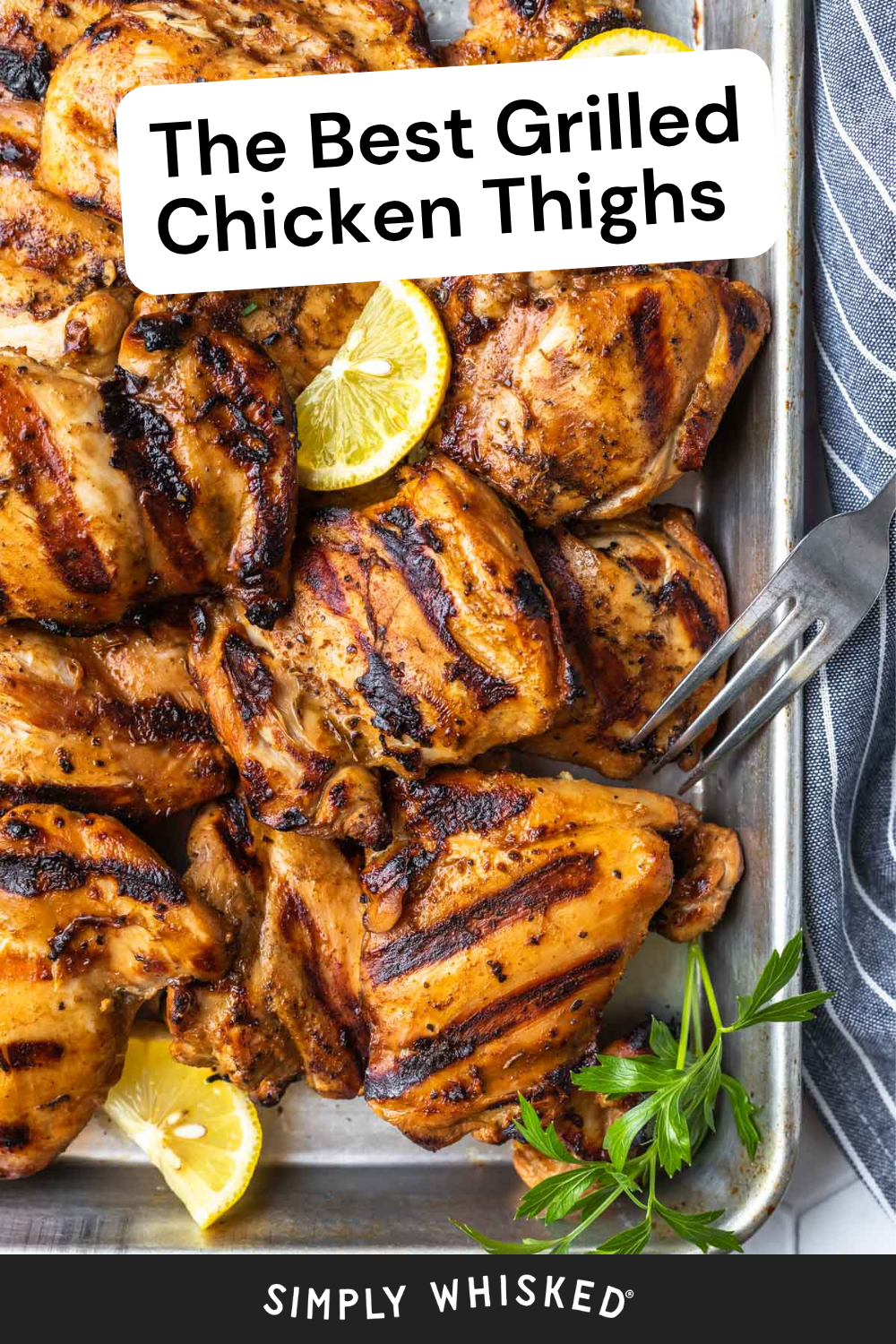Grilled chicken thighs on a metal tray, garnished with lemon slices and parsley, with a fork on the side. Text reads: The Best Grilled Chicken Thighs—perfectly juicy and flavorful grilled chicken thighs every time.