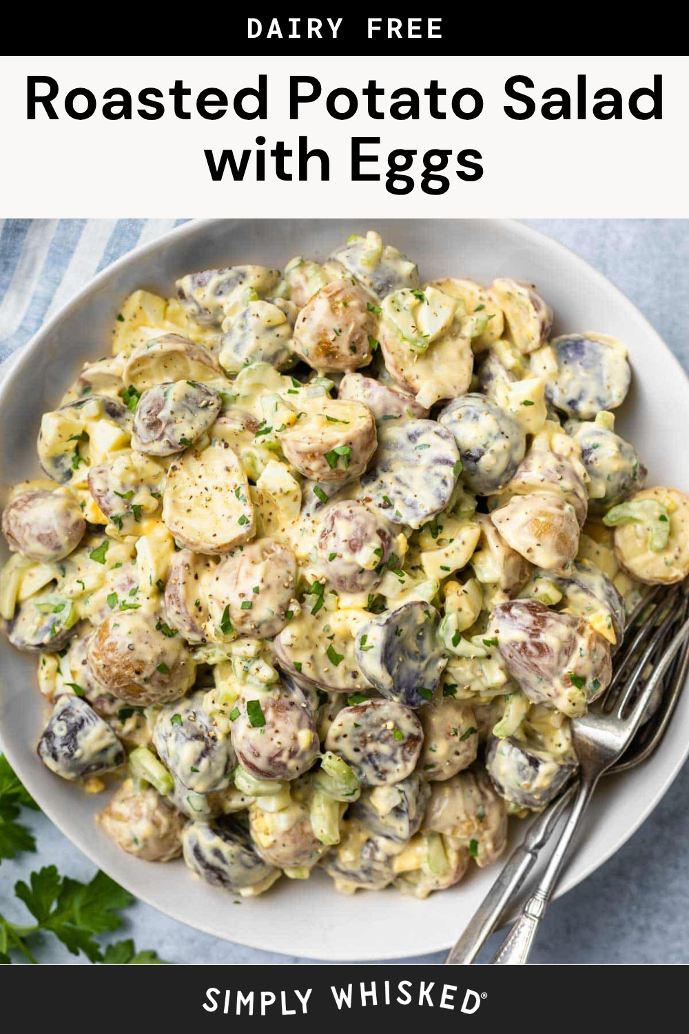 A bowl of roasted potato salad with chopped eggs, herbs, and a creamy dressing, served with two forks. The dish is labeled as dairy free.