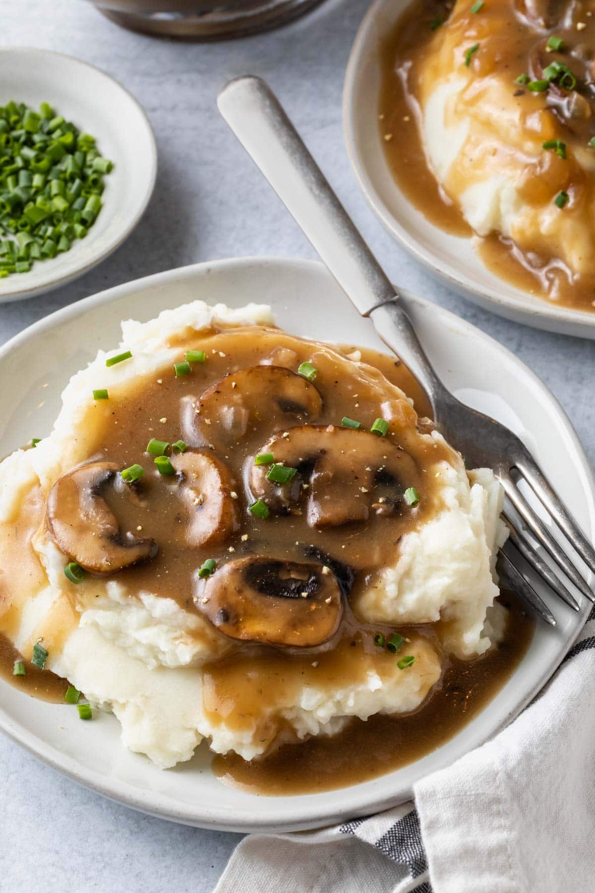 front view of vegan mushroom gravy on top of mashed potatoes with a fork