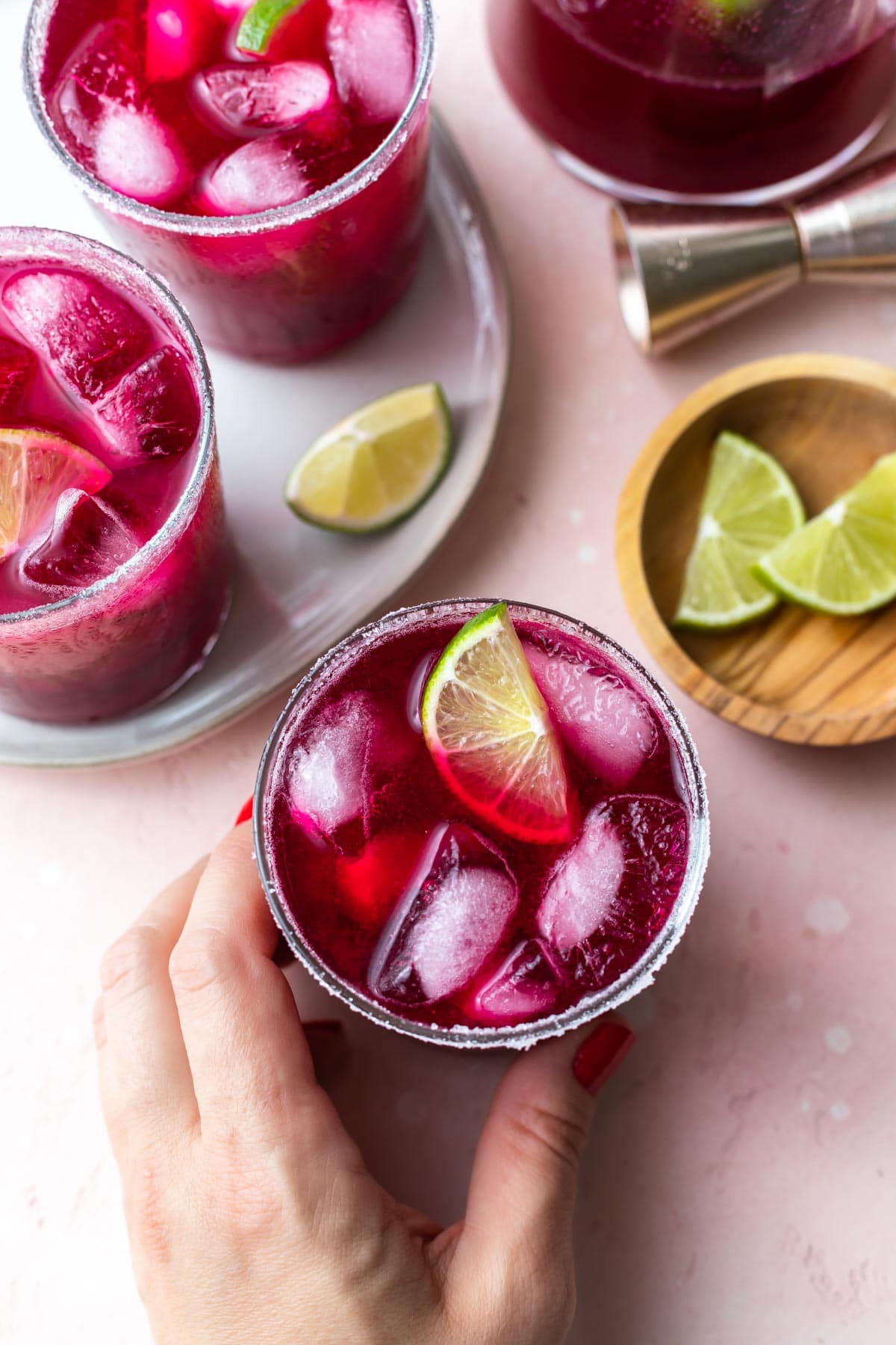hand taking a cocktail from a pink surface
