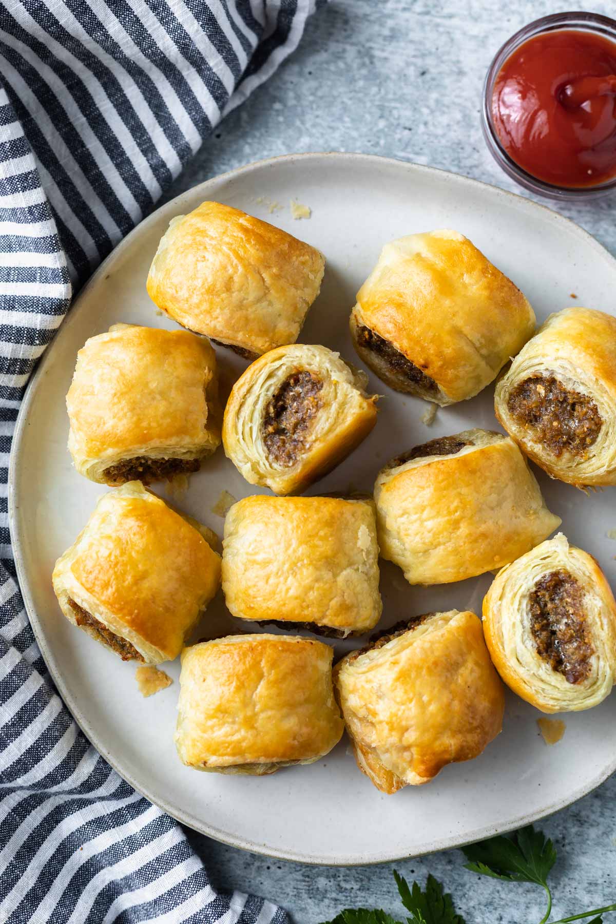 sausage rolls on a plate with a bowl of ketchup to the side
