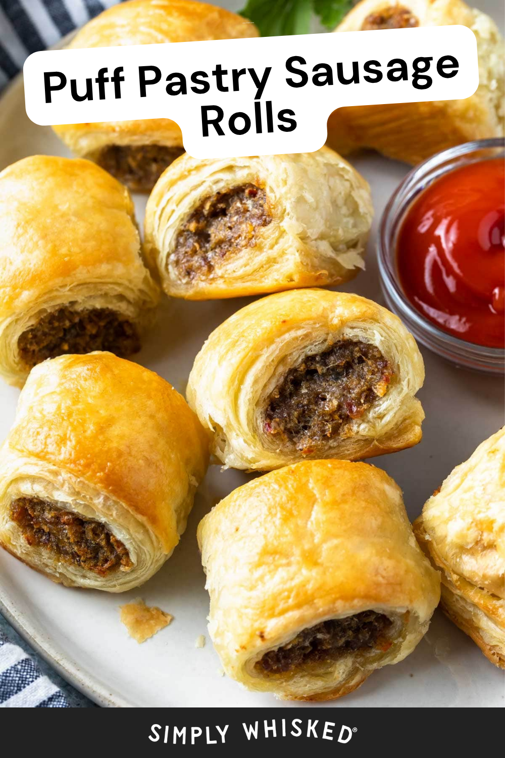 A plate of golden-brown puff pastry sausage rolls, some cut open to reveal their savory filling, is served with a small bowl of ketchup and a garnish of greens. The text reads Puff Pastry Sausage Rolls and Simply Whisked, perfectly capturing the irresistible appeal of these classic puff pastry sausage rolls.