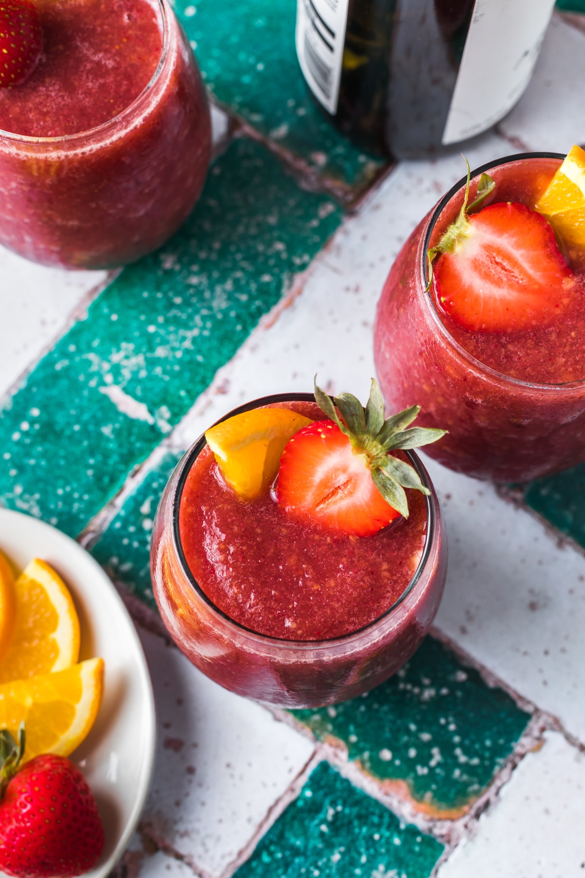 overhead view of frozen sangria with a slide of strawberry and orange next to two other glasses