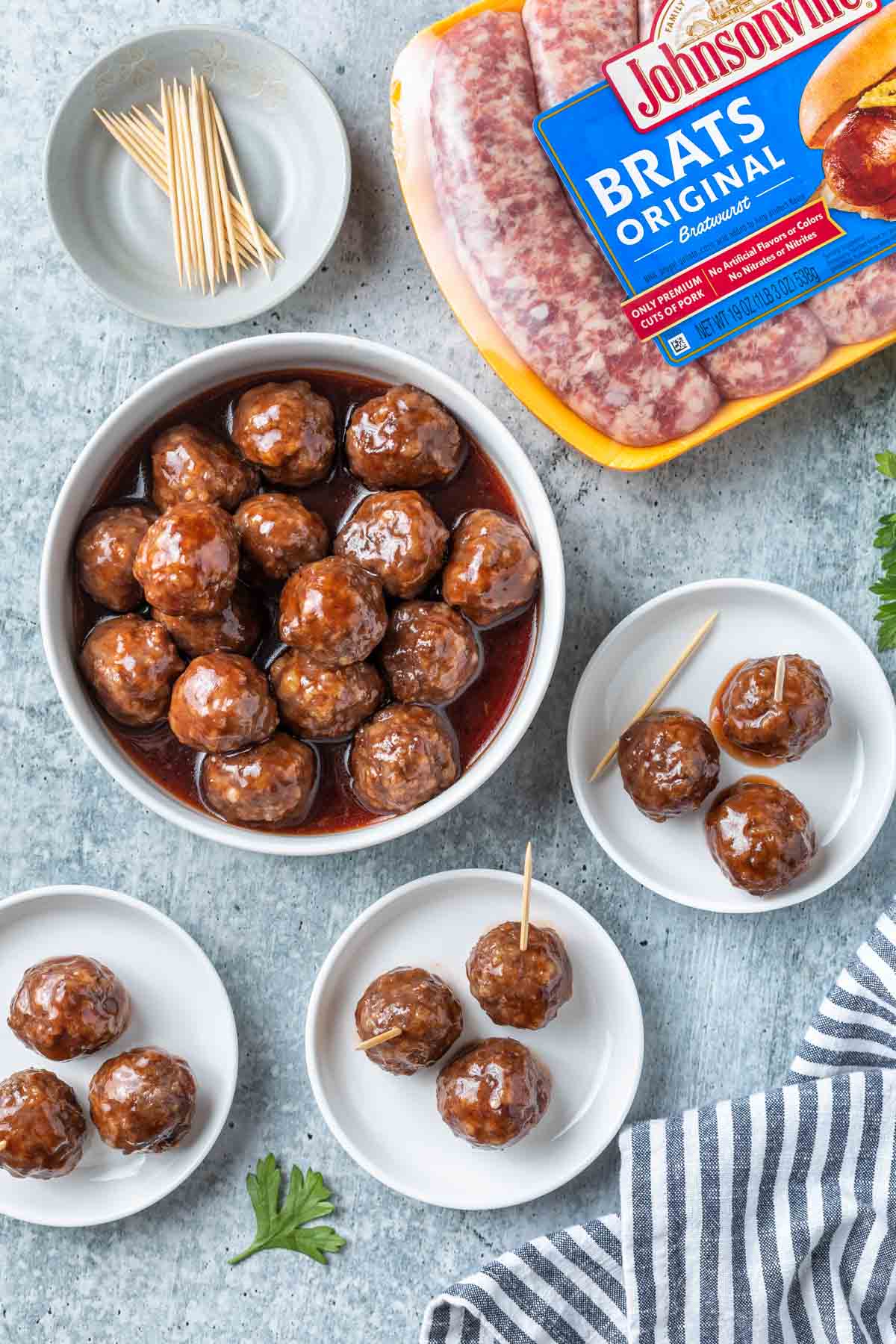 overhead image of a bowl of grape jelly meatballs and small serving plates with a meatballs and toothpicks