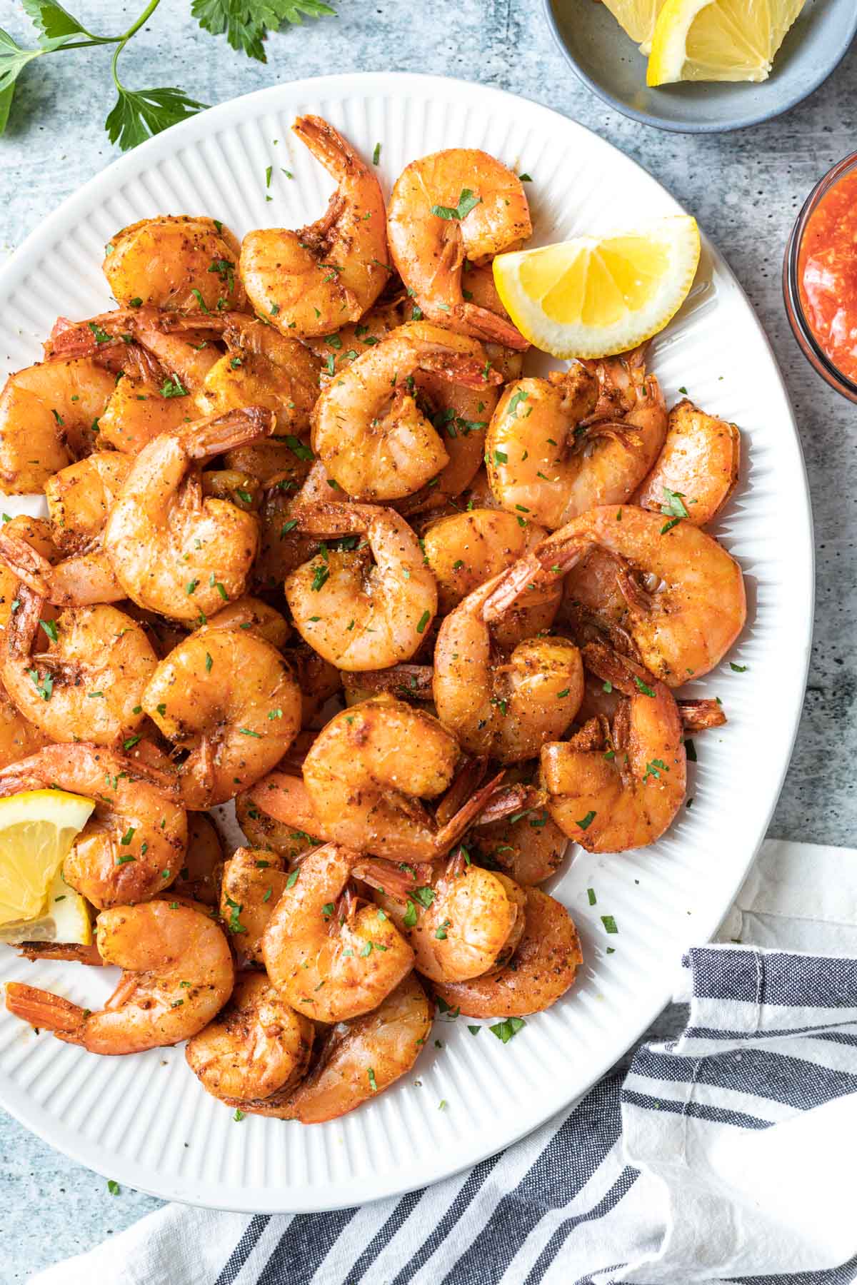 overhead view of baked shrimp on a large white plate with lemon slices