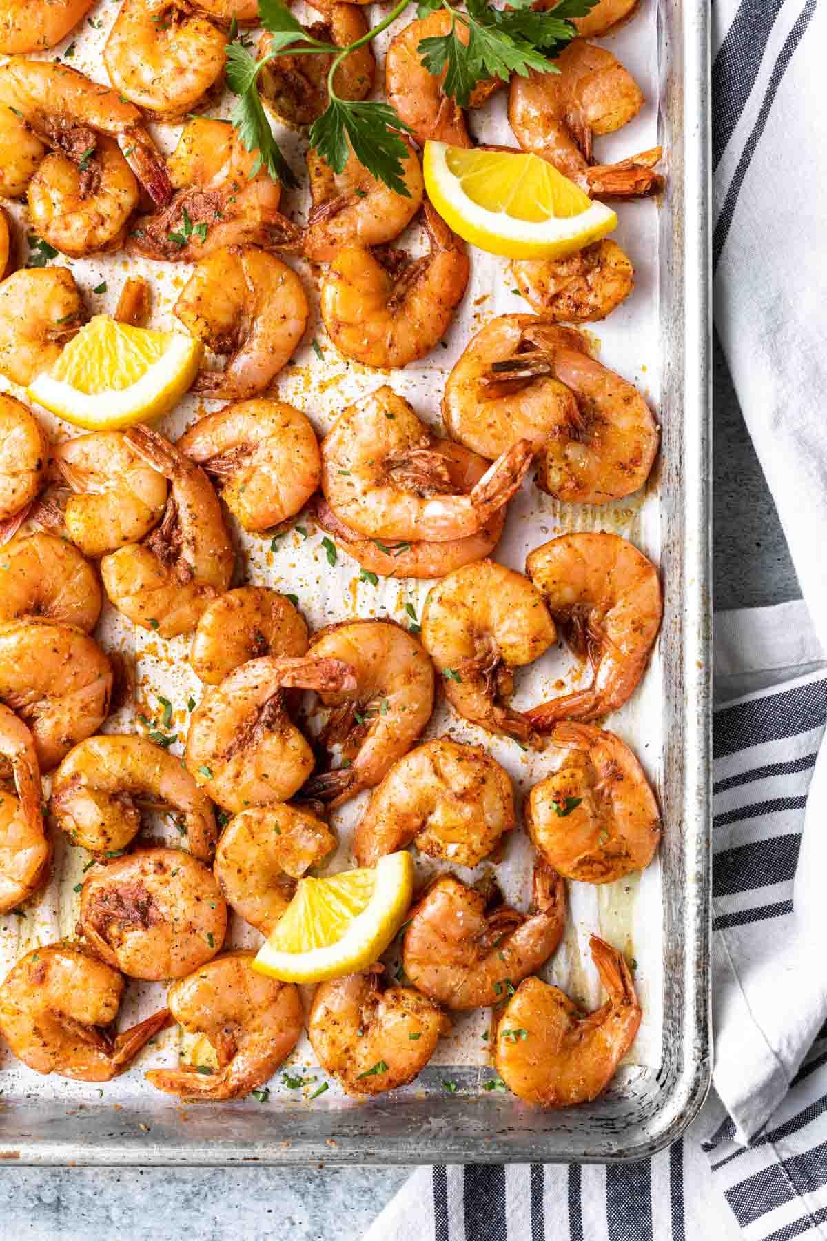 overhead view of shrimp with lemon slices on a sheet pan