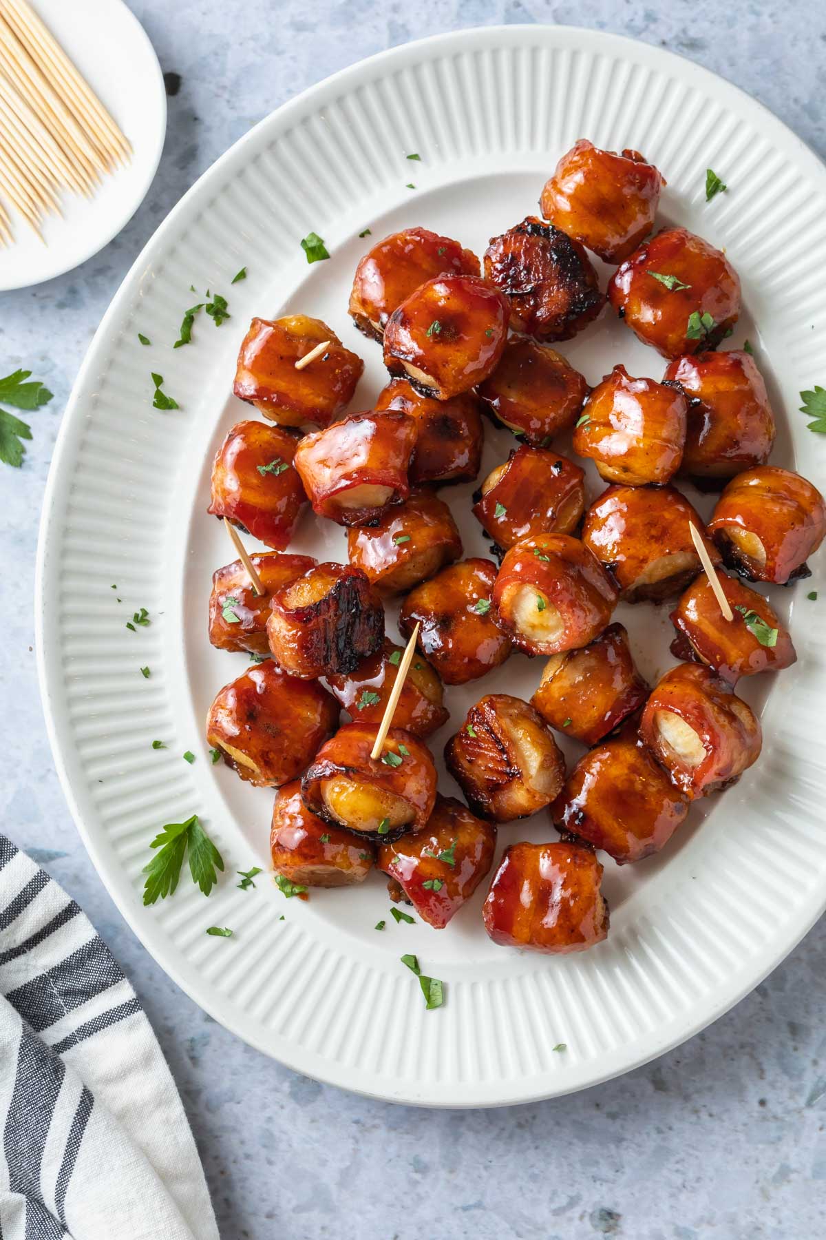 overhead view of bacon wrapped water chestnuts on a white serving plate