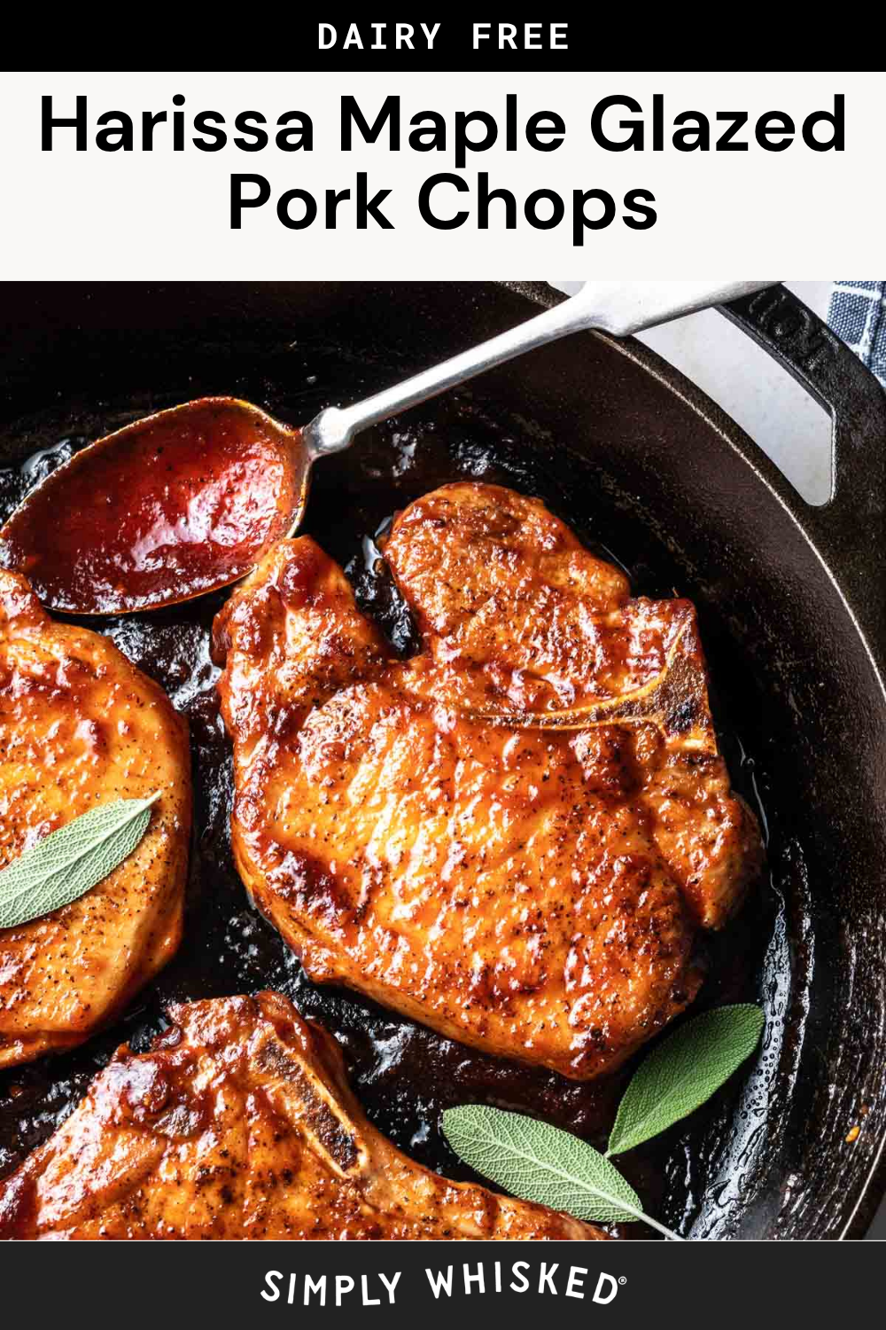 Harissa maple glazed pork chops sizzling in a cast iron skillet, beautifully garnished with fresh sage leaves. A spoon drizzles rich, flavorful sauce over one of the glazed pork chops. Text reads Dairy Free Harissa Maple Glazed Pork Chops.